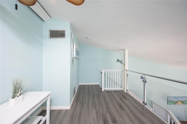 hallway featuring an upstairs landing, visible vents, baseboards, and wood finished floors