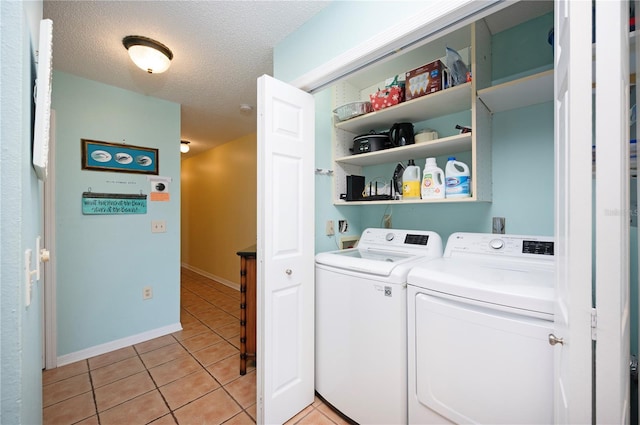 laundry room featuring baseboards, laundry area, light tile patterned flooring, a textured ceiling, and washing machine and dryer