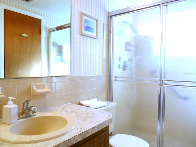 full bathroom featuring toilet, a stall shower, tile walls, wallpapered walls, and vanity