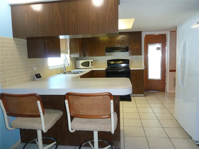 kitchen featuring white appliances, light tile patterned floors, a sink, light countertops, and under cabinet range hood