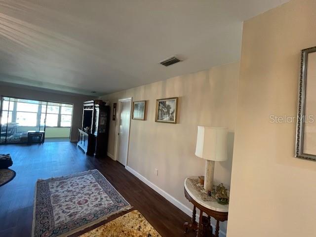 hall with baseboards, visible vents, and wood finished floors