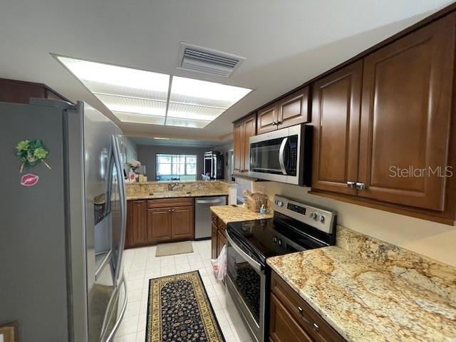 kitchen featuring stainless steel appliances, a sink, visible vents, and light stone countertops