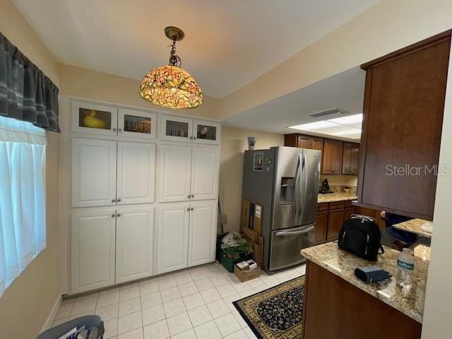 kitchen featuring light tile patterned floors, visible vents, glass insert cabinets, hanging light fixtures, and stainless steel refrigerator with ice dispenser