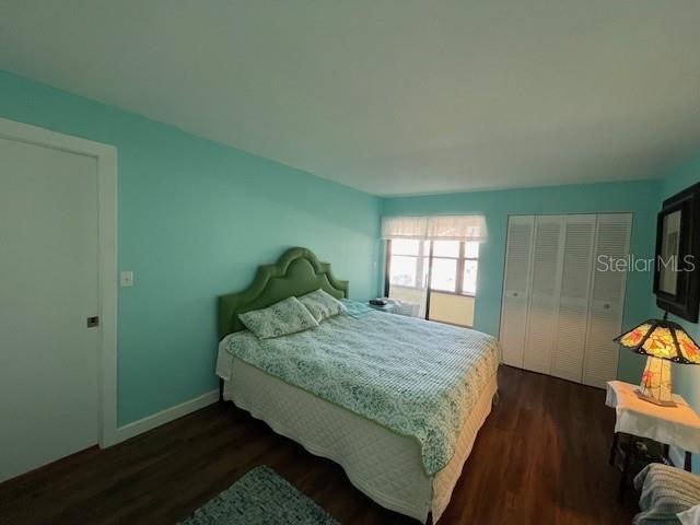 bedroom with a closet, dark wood-style flooring, and baseboards