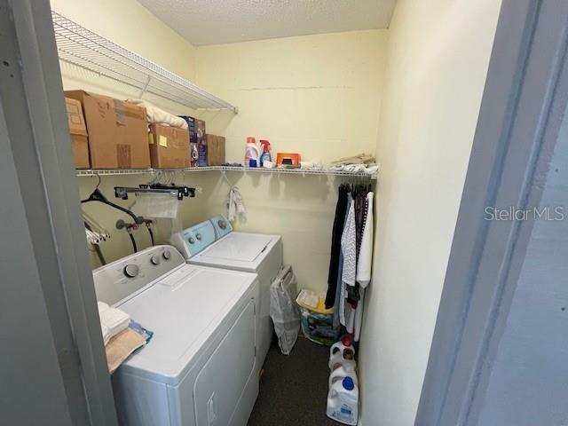 washroom with laundry area, washing machine and dryer, and a textured ceiling