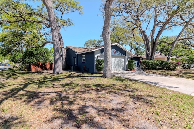 view of home's exterior with a yard, central AC unit, driveway, and a garage