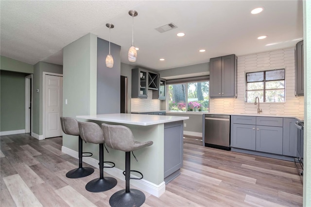 kitchen featuring a kitchen bar, light wood-type flooring, visible vents, a sink, and stainless steel dishwasher