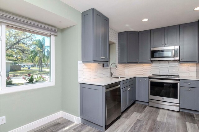 kitchen with a sink, appliances with stainless steel finishes, gray cabinets, and light countertops