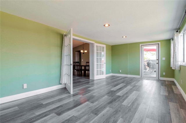 spare room with recessed lighting, a notable chandelier, wood finished floors, and baseboards