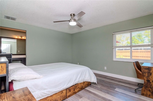 bedroom featuring visible vents, baseboards, a textured ceiling, and wood finished floors