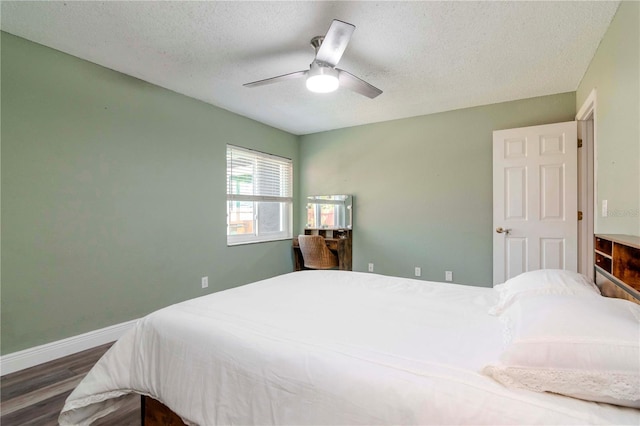 bedroom featuring baseboards, a textured ceiling, wood finished floors, and a ceiling fan