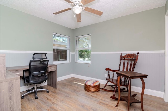 office featuring ceiling fan, baseboards, light wood-type flooring, and a textured ceiling