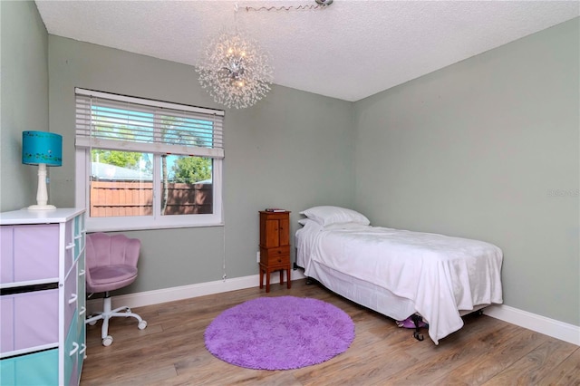 bedroom featuring baseboards, wood finished floors, and a chandelier