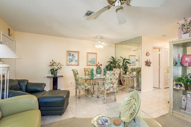 living area featuring light tile patterned flooring, a ceiling fan, visible vents, and a textured ceiling