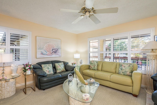 living area featuring baseboards, a textured ceiling, ceiling fan, and carpet flooring