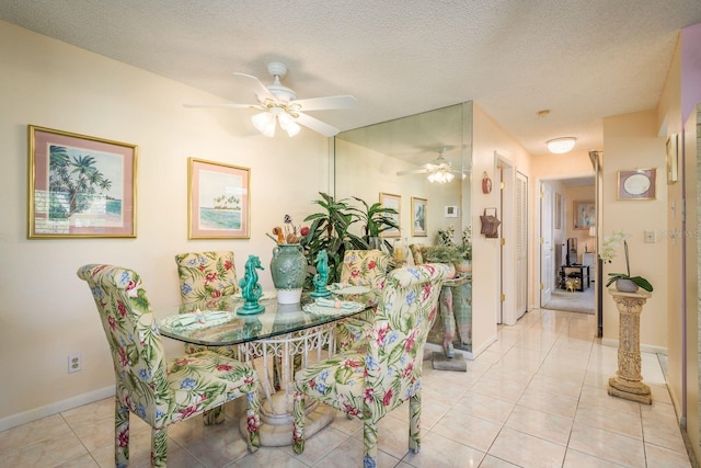 dining area with light tile patterned flooring, a ceiling fan, baseboards, and a textured ceiling