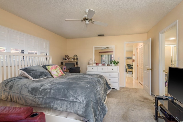 bedroom with ceiling fan, light colored carpet, visible vents, and a textured ceiling