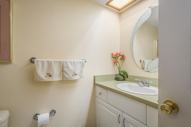 bathroom featuring toilet, a skylight, and vanity