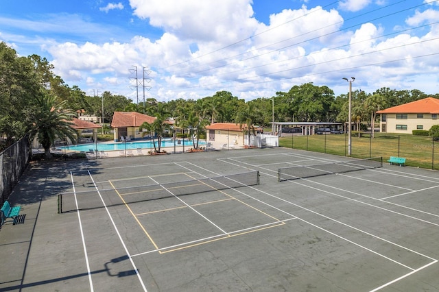 view of tennis court with a community pool and fence