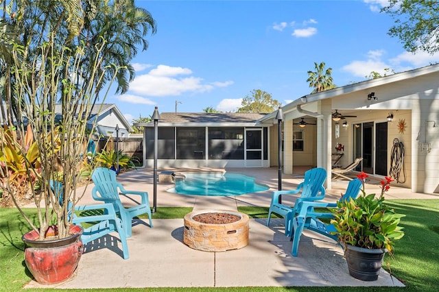 view of pool featuring a fire pit, fence, a sunroom, a patio area, and a ceiling fan