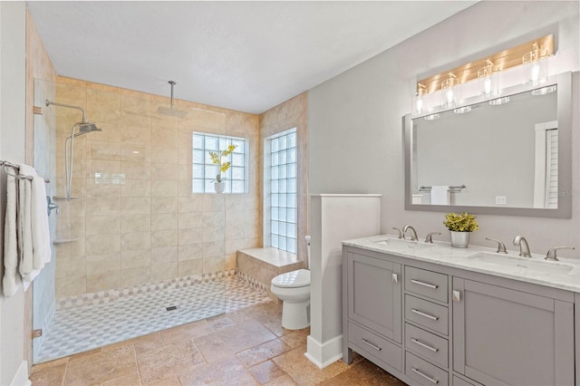 full bathroom featuring a sink, tiled shower, and toilet