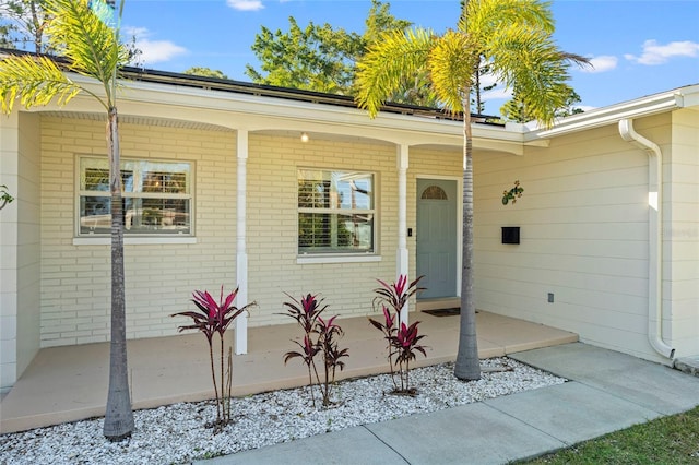 entrance to property with brick siding and a porch