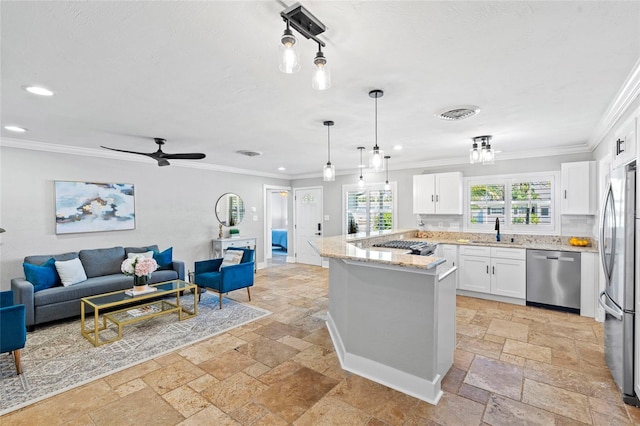 kitchen featuring a sink, open floor plan, stone tile flooring, appliances with stainless steel finishes, and crown molding