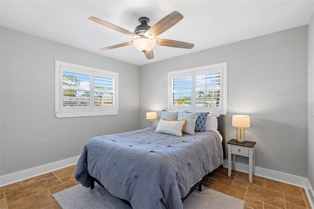 bedroom with stone finish floor, multiple windows, and baseboards