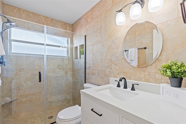 bathroom with toilet, tile walls, a stall shower, and vanity