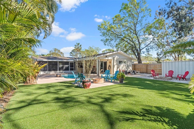 back of property featuring a fire pit, fence, a yard, a sunroom, and a patio area