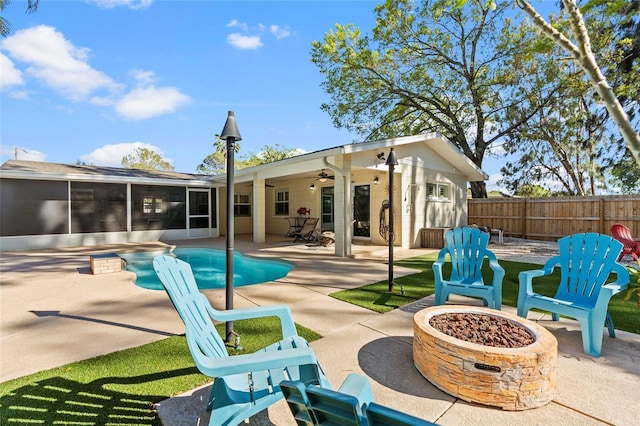 view of swimming pool with a ceiling fan, fence, a sunroom, a fire pit, and a patio area