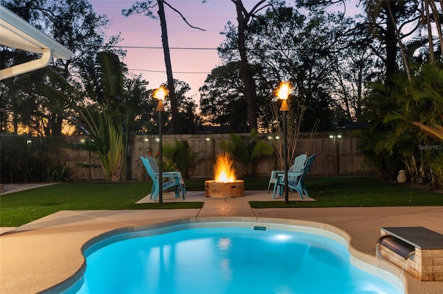 pool at dusk with a fenced in pool, an outdoor fire pit, a lawn, a fenced backyard, and a patio