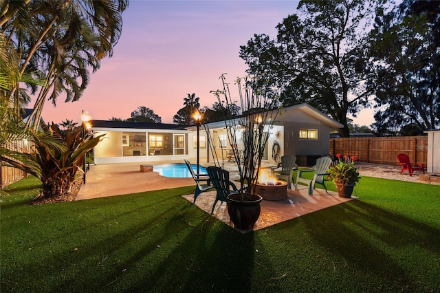 back of property at dusk with a patio area, a lawn, and an outdoor fire pit