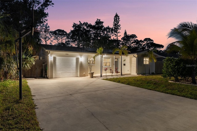 view of front of property with concrete driveway, an attached garage, fence, and a front lawn