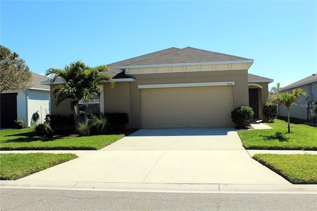 ranch-style home with driveway, a front lawn, an attached garage, and stucco siding