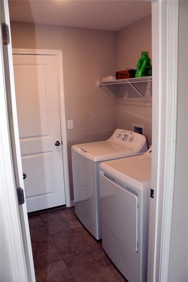 clothes washing area with laundry area, separate washer and dryer, a textured ceiling, and tile patterned floors