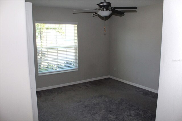 empty room featuring baseboards, dark carpet, and ceiling fan