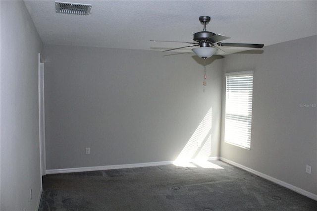 carpeted empty room featuring a ceiling fan, visible vents, and baseboards