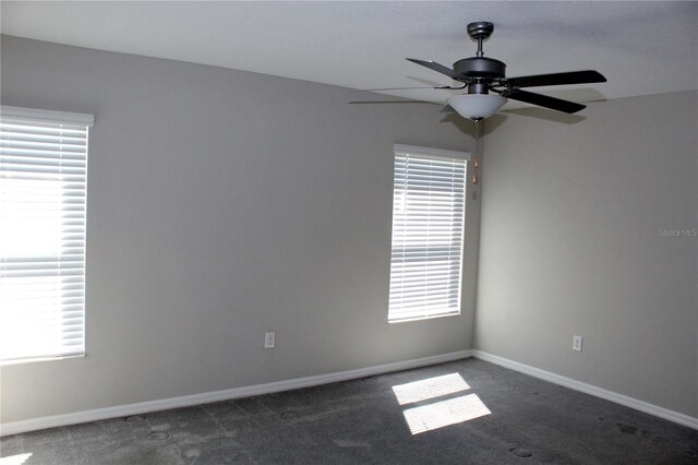 carpeted spare room featuring ceiling fan and baseboards