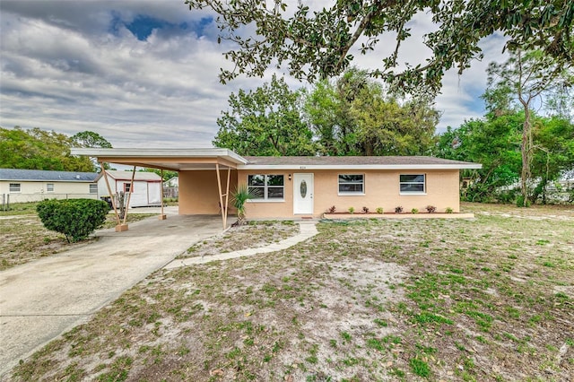 single story home with an outbuilding, a carport, and concrete driveway