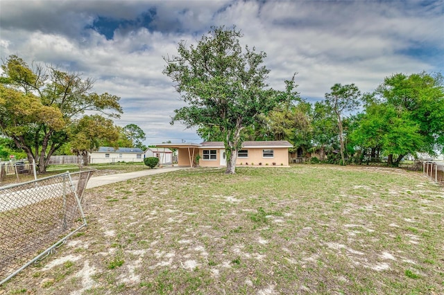 ranch-style home featuring fence, an attached carport, concrete driveway, and a front yard