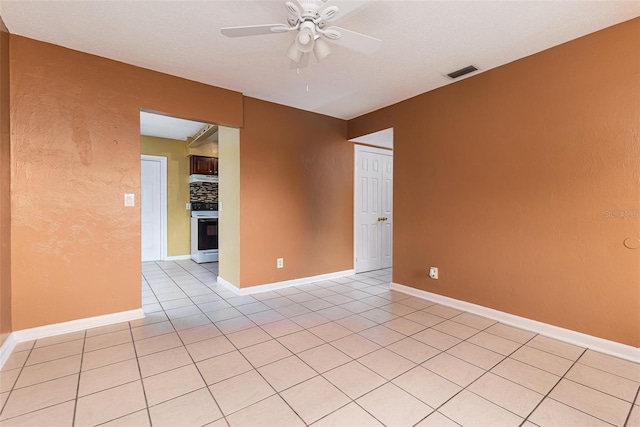 empty room featuring light tile patterned floors, baseboards, visible vents, and a ceiling fan