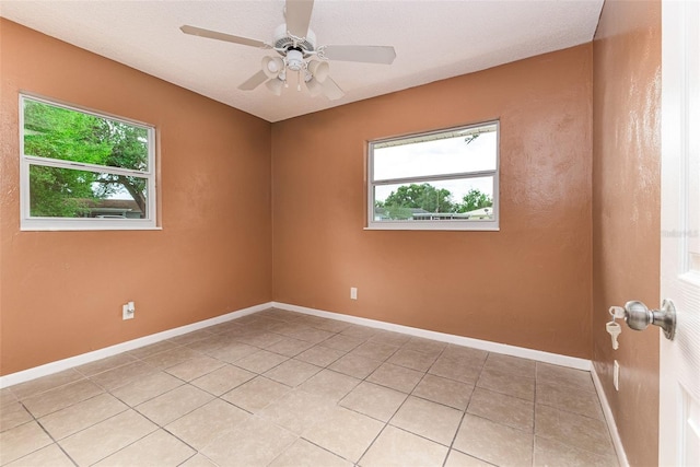 unfurnished room featuring light tile patterned flooring, a ceiling fan, and baseboards