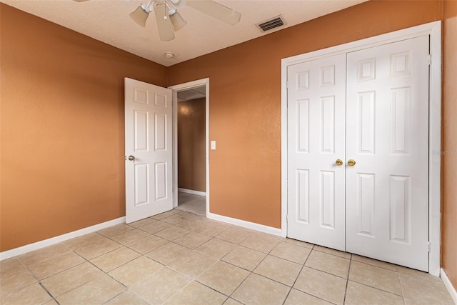 unfurnished bedroom with a closet, visible vents, a ceiling fan, light tile patterned flooring, and baseboards