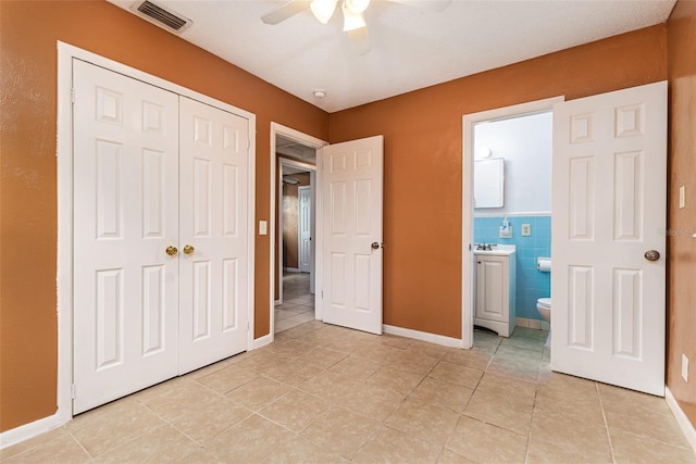 unfurnished bedroom featuring a closet, visible vents, connected bathroom, and light tile patterned flooring