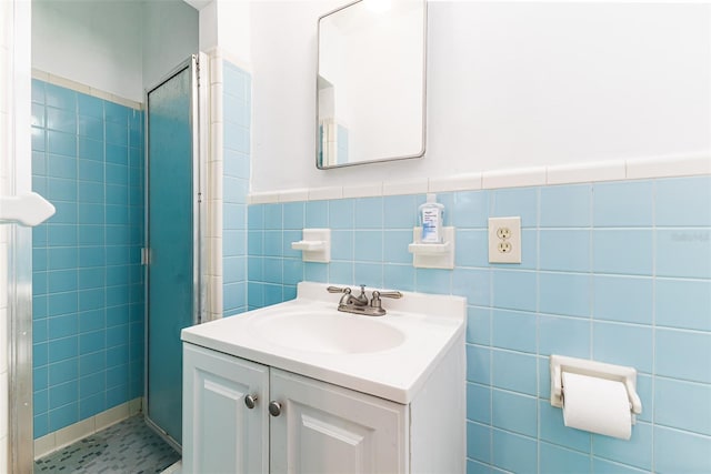 bathroom with wainscoting, a tile shower, tile walls, and vanity