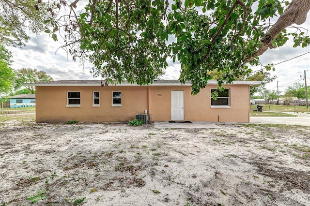 back of house with stucco siding, fence, and central AC unit