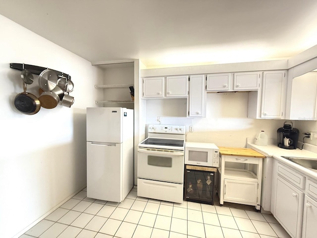 kitchen featuring white appliances, light tile patterned floors, white cabinetry, and a sink