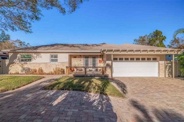 single story home with decorative driveway, french doors, a garage, and stucco siding