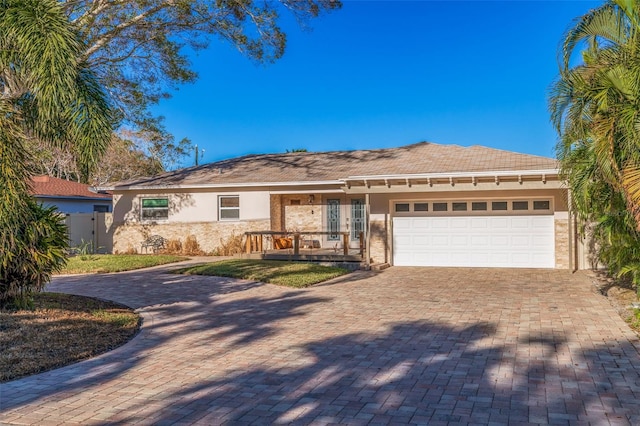 ranch-style home with decorative driveway, fence, a garage, and stucco siding